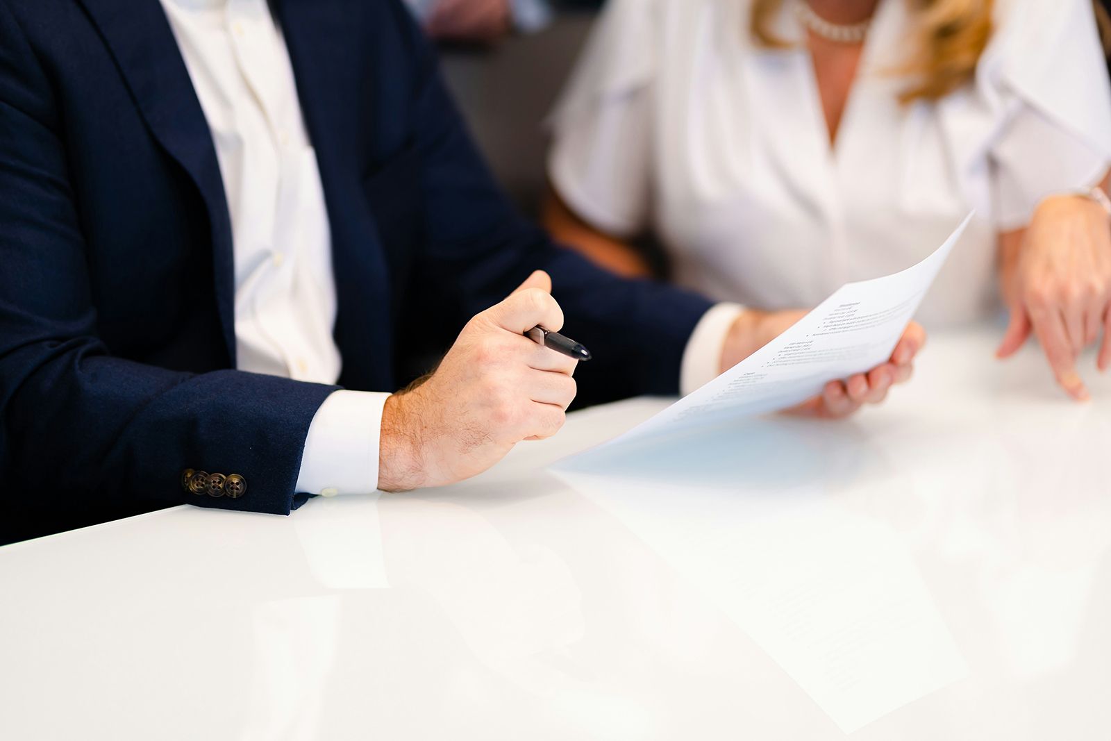 Two people reviewing a printed assessment at a white table, one holding a pen